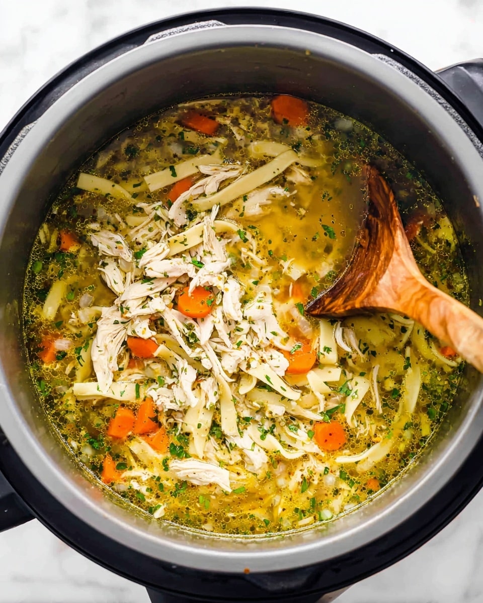 A white bowl filled with clear chicken soup with three layers visible: the bottom layer is a light yellowish broth with herbs sprinkled throughout, the middle layer has thick, soft, wavy egg noodles in a light golden color, and the top layer shows shredded chicken pieces and small bright orange carrot slices, all floating gently. A silver spoon is placed inside the bowl on the right side. The bowl rests on a white marbled surface with a light cloth beneath. In the blurred background, more white bowls and green herbs are seen. Photo taken with an iphone --ar 4:5 --v 7