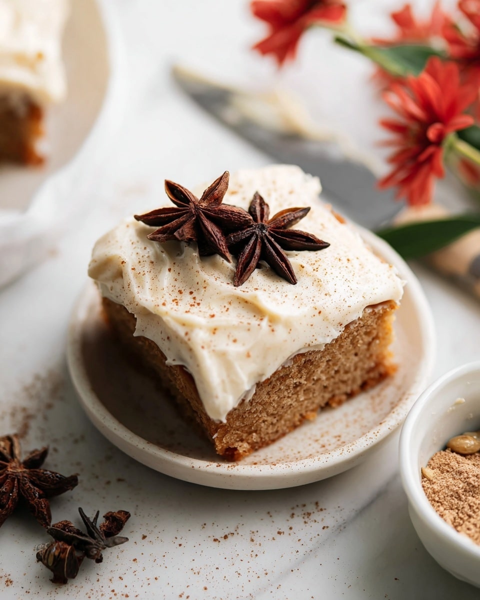 A square piece of light brown cake topped with a thick layer of creamy off-white frosting, sprinkled lightly with a fine dusting of cinnamon or nutmeg, and decorated on top with two dark brown star anise spices. The cake is set on a white plate with a smooth, shiny surface. Nearby, there is a small white bowl filled with brown sugar and another star anise, with some red flowers and green leaves partially visible, all placed on a white marbled surface. A blurred knife with frosting on its blade is in the background. photo taken with an iphone --ar 4:5 --v 7