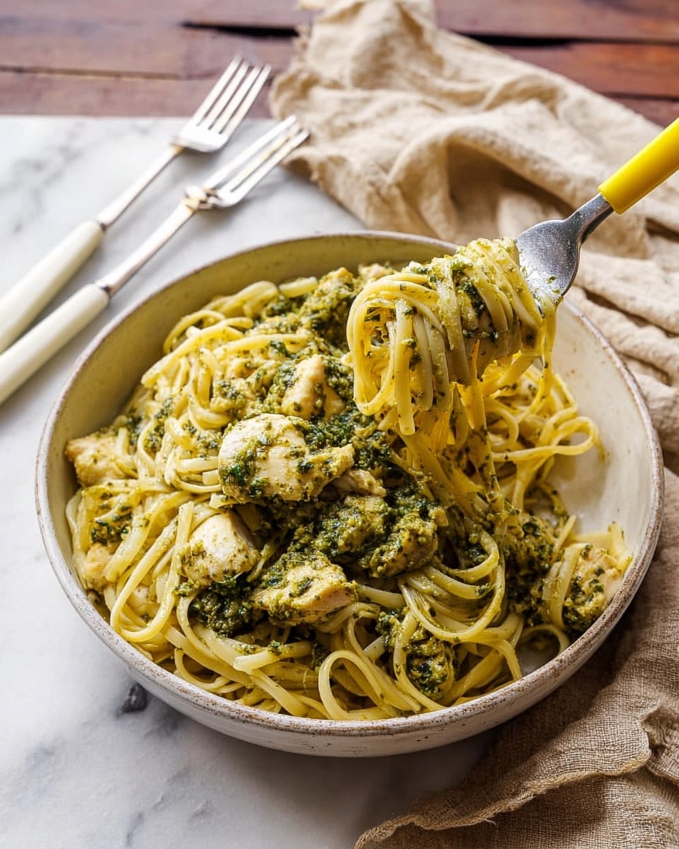 A white bowl filled with long, tangled spaghetti noodles that are light yellow in color, topped with pieces of chicken covered in a green herb sauce. The noodles have a light shine, and the green sauce on the chicken looks thick with small bits of herbs spread unevenly. The bowl is placed on a dark, wooden surface. photo taken with an iphone --ar 4:5 --v 7