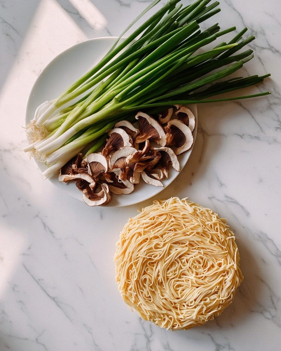 The image shows two white dishes on a white marbled surface. The top white plate holds a bunch of long, green onion stalks covering half the plate, and in front of them are several sliced brown mushrooms with light and dark brown textures. Below the plate on the marble surface lies a round, flat nest of pale yellow noodles, arranged tightly in a circular shape with uneven strand patterns. The photo is taken with an iphone --ar 4:5 --v 7