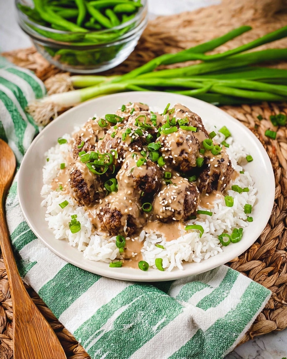 A white plate filled with a bed of white rice as the bottom layer, topped with dark brown, round, crispy textured meatballs. The meatballs are covered with a creamy light brown sauce and sprinkled with small green onion pieces and white sesame seeds. The plate sits on a woven mat with a green and white striped cloth underneath. To the side, there is a glass bowl filled with bright green cooked green beans and a bunch of fresh green onions laying beside the plate. A wooden spoon is also partially visible on the mat. Photo taken with an iphone --ar 4:5 --v 7