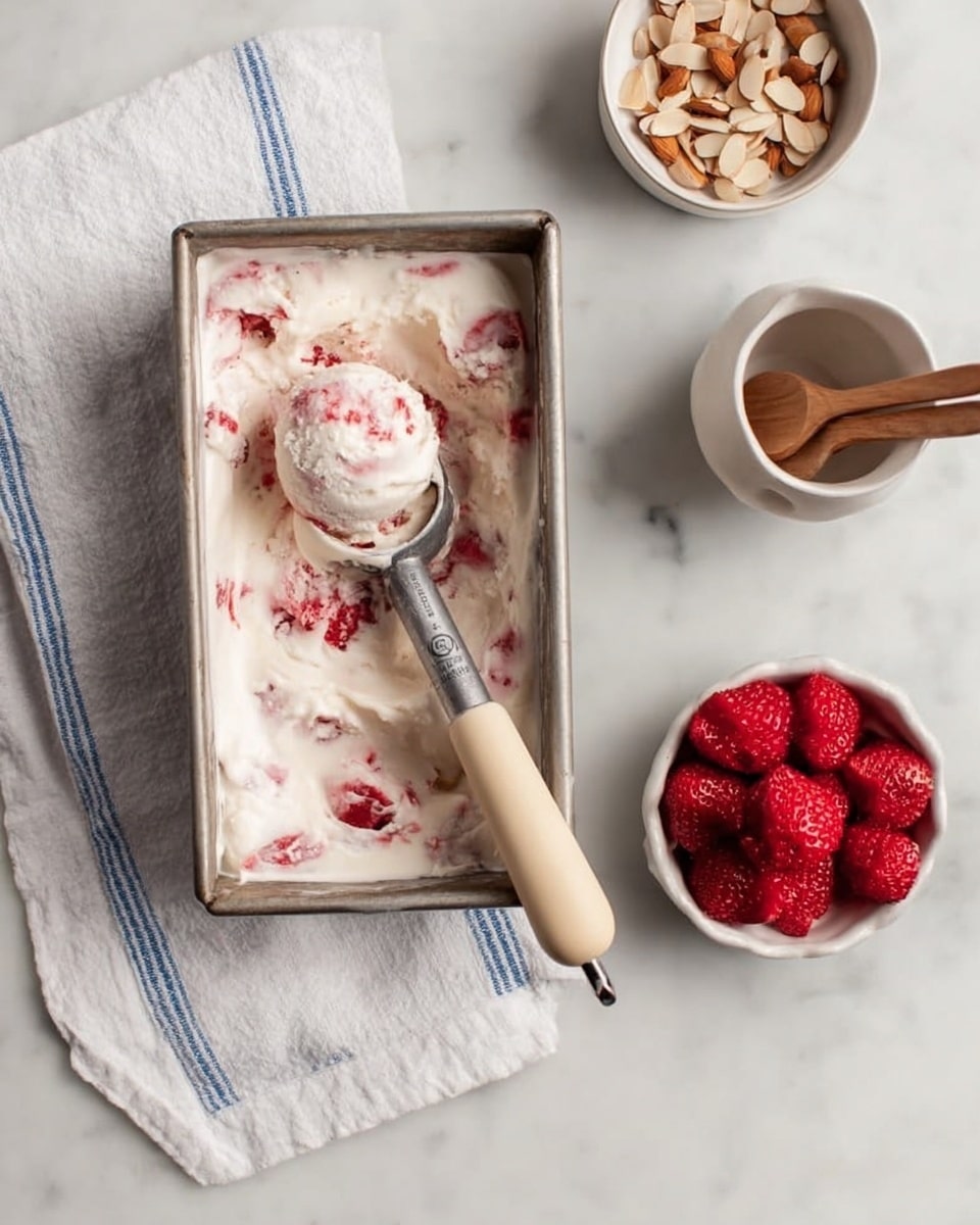 The image shows a loaf pan lined with white parchment paper filled with creamy white ice cream mixed with small red fruit pieces swirled throughout. The texture looks smooth and soft with visible waves and folds in the ice cream, and parts of the red fruit are faintly visible under the surface. The pan is placed on a white marbled surface, and some ice cream is slightly overflowing the edges of the parchment paper. The scene is clean and bright, focusing closely on the pan and its contents. photo taken with an iphone --ar 4:5 --v 7
