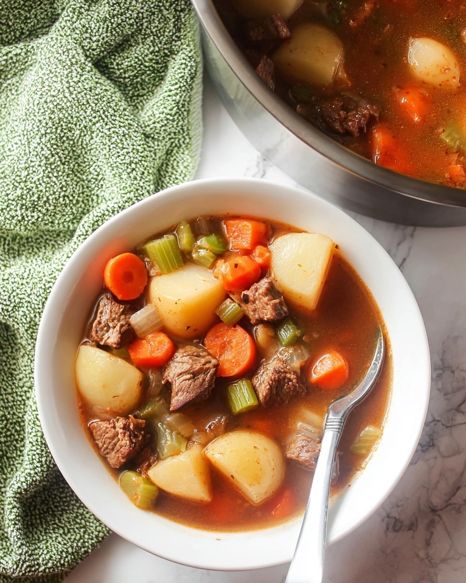 A white bowl filled with a beef stew that has multiple layers of ingredients: large chunks of light tan potatoes, bright orange carrot pieces, green celery slices, and tender brown beef cubes, all soaked in a rich brown broth. A white spoon with a silver handle rests inside the bowl on the right side. Behind the bowl, a large silver pot with more stew is partially visible on a white marbled surface, next to a green and white textured cloth. The colors range from orange to light brown, green, and rich brown, giving a hearty, warm look. Photo taken with an iphone --ar 4:5 --v 7