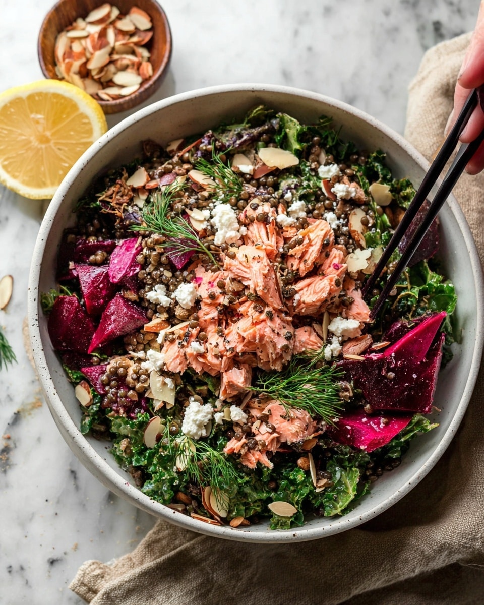 A large white bowl filled with a colorful salad featuring a mix of layers: the bottom has dark green leafy kale, topped with bright pink beet slices and small dark lentils scattered throughout. On top, chunks of cooked pink salmon are placed, mixed with white crumbled cheese. Thin, light brown toasted almond slices are sprinkled over the salad, adding texture. Fresh sprigs of green dill are visible among the ingredients. The bowl is set on a white marbled surface, with a woman's hand holding black chopsticks gently touching the salad from above. A sliced lemon and a small bowl of almond slices are partially visible near the top left corner. photo taken with an iphone --ar 4:5 --v 7