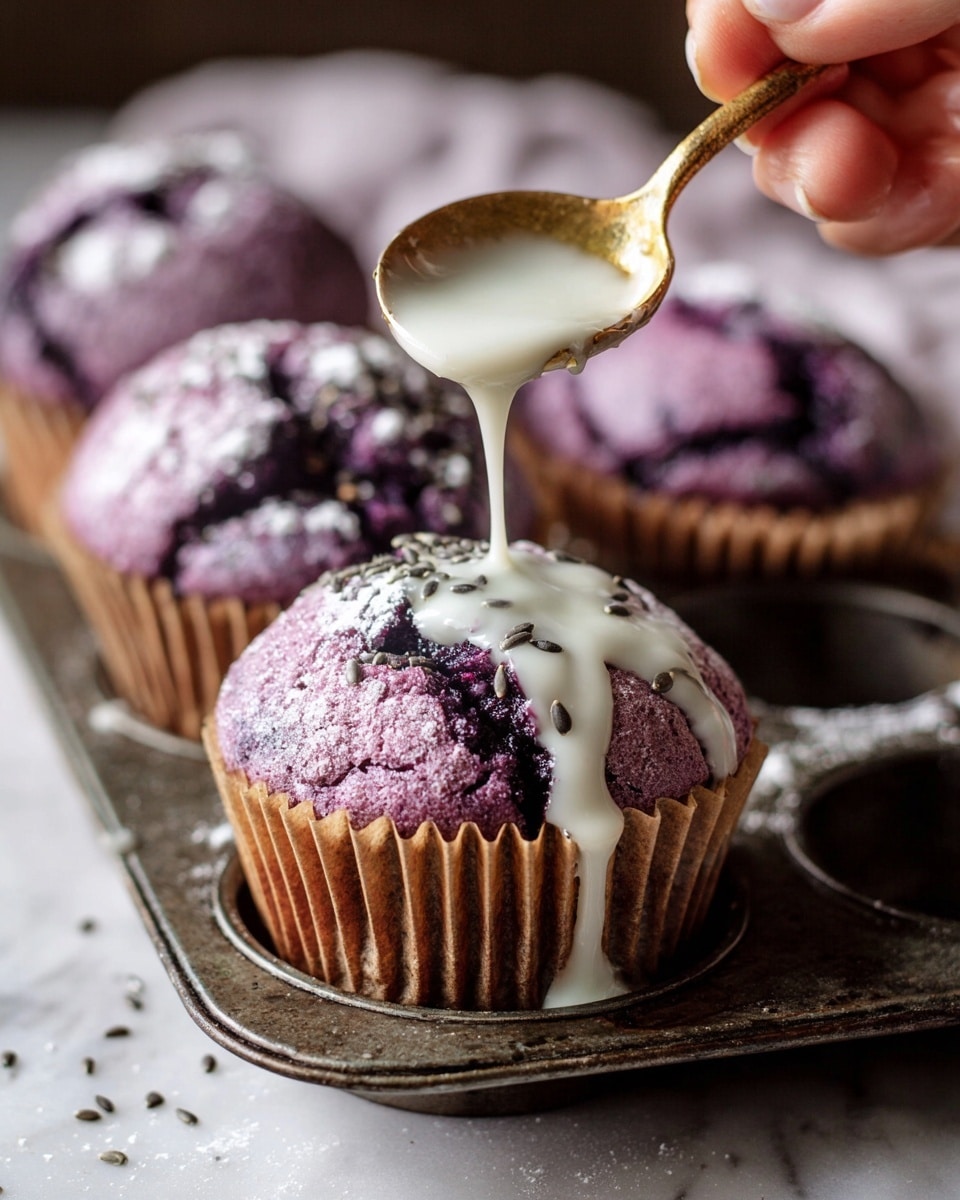 A close-up of a purple muffin with a cracked top, dusted lightly with white powdered sugar and some dark small seeds on top, sitting in a brown paper liner placed on an old metal muffin tray with raised round mold shapes; a woman's hand is holding a small gold spoon above the muffin, pouring smooth white glaze that flows down into the cracks and side of the muffin, with more purple muffins blurred in the background on a white marbled surface. Photo taken with an iphone --ar 4:5 --v 7
