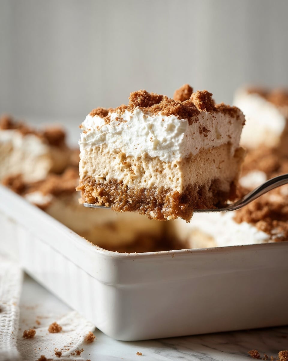 A close-up of a square piece of dessert being lifted from a white rectangular baking dish, showing two layers: the bottom layer is thick and creamy with a light brown color and slightly crumbly texture, while the top layer is a thick, fluffy white cream sprinkled with small brown crumbs. The dish is set on a white marbled surface with more pieces of the dessert visible in the background, all under soft natural light. Photo taken with an iphone --ar 4:5 --v 7
