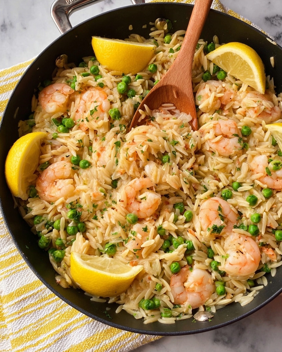 A black skillet filled with a mixture of light golden orzo pasta, pink shrimp, and green peas all mixed together. Small pieces of white onion are visible throughout. On top, bright yellow lemon wedges are placed around, adding color contrast. A wooden spoon rests inside the skillet on the right side, partially stirring the dish. The skillet sits on a white marbled surface with a blurred background showing a packet and a lemon half. Photo taken with an iphone --ar 4:5 --v 7