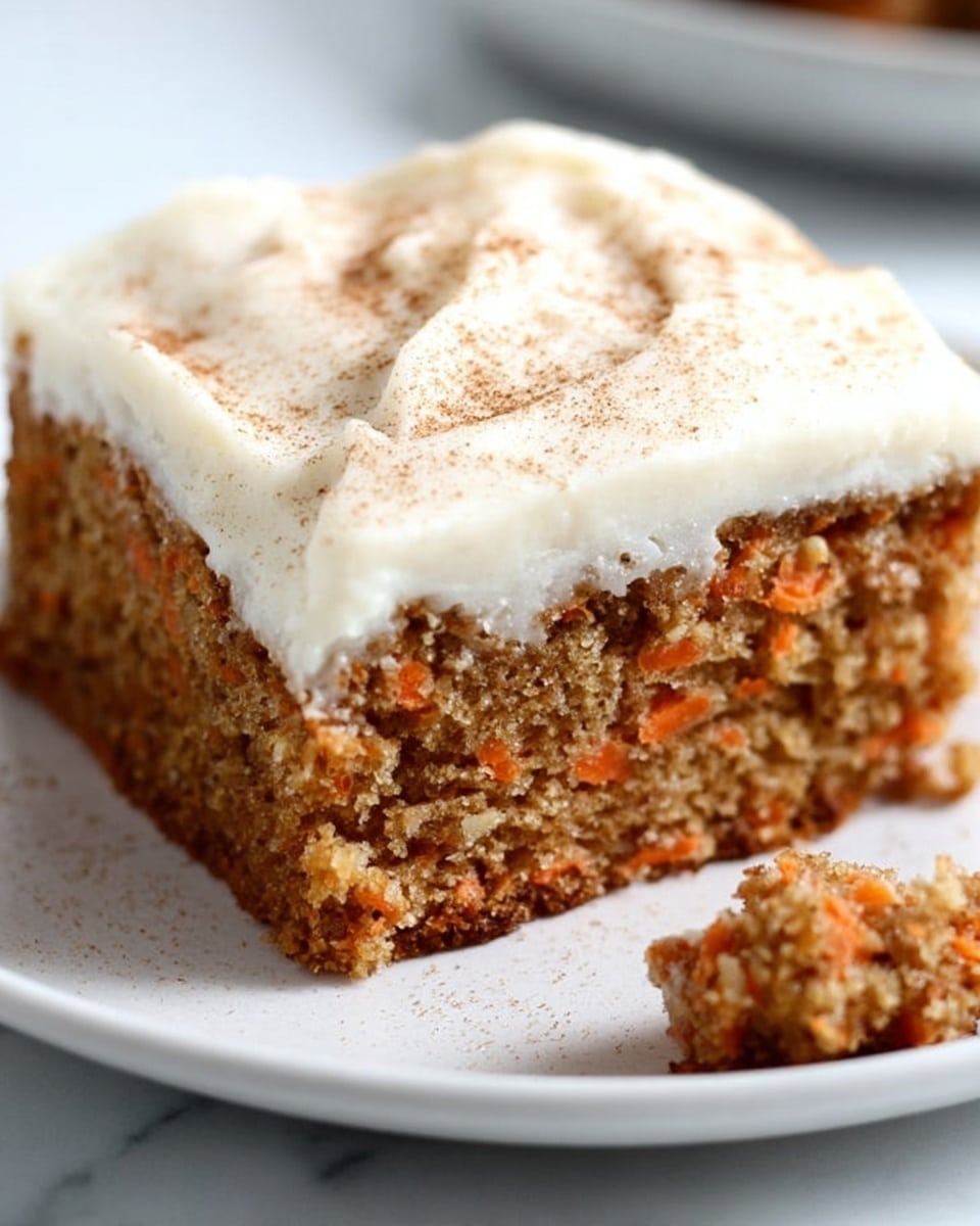 A close-up shot of a single square piece of carrot cake on a white plate, showing two layers: the bottom layer is a thick, moist carrot cake with small orange carrot bits and a slightly crumbly texture, while the top layer is a smooth, thick white cream cheese frosting that covers the cake unevenly with soft peaks and a light dusting of cinnamon powder. The cake is positioned slightly off-center on the plate, and a small piece of the cake is broken off in the foreground. The background is a white marbled texture. photo taken with an iphone --ar 4:5 --v 7