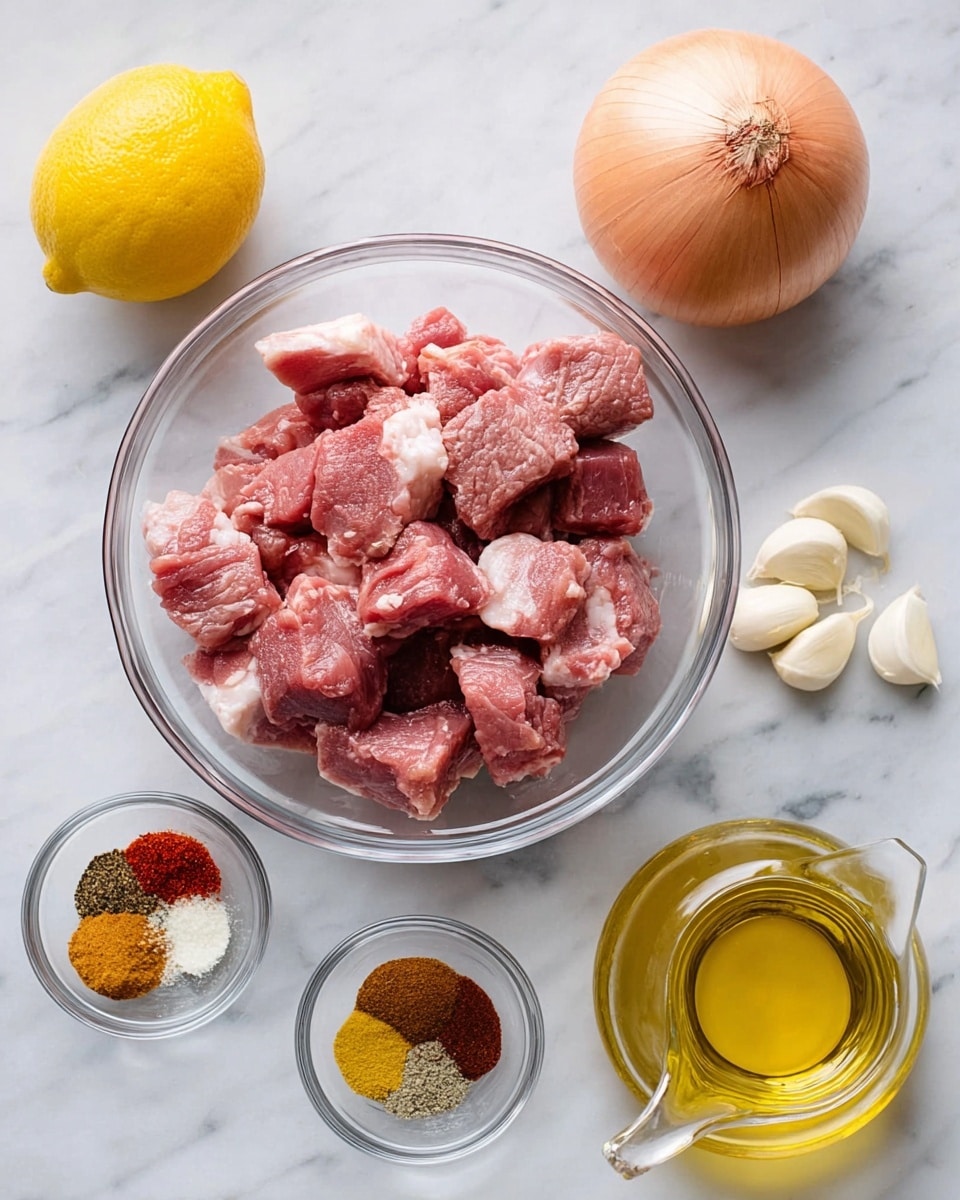 The image shows several clear glass bowls and fresh ingredients arranged neatly on a white marbled surface. In the center is a large clear bowl filled with raw pinkish-red meat chunks with some white fat. To the bottom left is a smaller clear bowl holding five different spices in small piles of red, brown, yellow, black, and white colors. Above that is another small clear bowl containing three peeled garlic cloves. On the left side, there is a bright yellow whole lemon. To the right top corner, a whole yellow onion with a papery skin is placed. At the bottom right is a small clear glass container with a golden-yellow liquid, likely olive oil, with a spout on top. The photo taken with an iphone --ar 4:5 --v 7