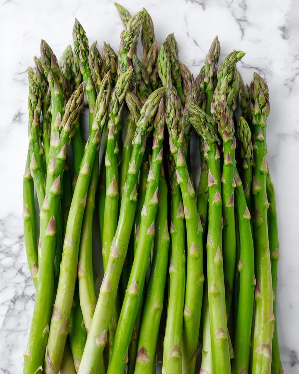 A bunch of fresh green asparagus spears is neatly laid out in a row on a white marbled surface. The asparagus stalks are bright green with slightly purplish tips, and they vary in thickness and length but mostly stay parallel and close to each other. The texture of the spears is smooth with visible small triangular scales along the stalks. The overall look is clean, fresh, and ready for cooking or serving, with no other objects in the frame. photo taken with an iphone --ar 4:5 --v 7