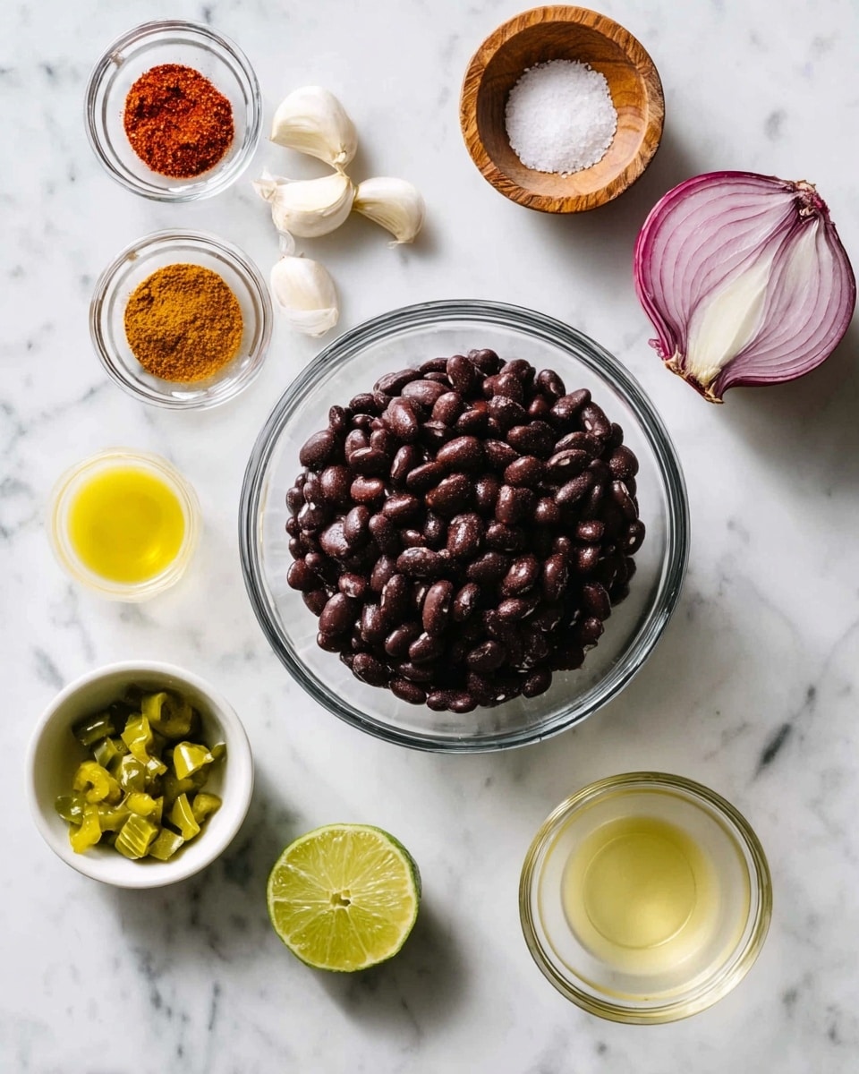 The image shows a clear glass bowl filled with dark black beans in the center, resting on a white marbled surface. Surrounding the bowl, starting from the top right corner, is a half red onion with a smooth cross-section showing white and purple layers; below it, three cloves of garlic are scattered. On the top left side, two small glass bowls hold red spice powder and yellow-brown spice powder, with a wooden bowl containing coarse salt between them. Below the spices, a quarter of a lime with bright green-yellow skin sits next to two wedges of the same lime, one of which is slightly squeezed. In the bottom left corner, a white bowl contains chopped green peppers. To the right of this bowl, two small clear glass bowls hold light yellow olive oil and a pale beige liquid. The overall setting is neatly arranged on a white marbled surface that gives a clean and fresh look. photo taken with an iphone --ar 4:5 --v 7