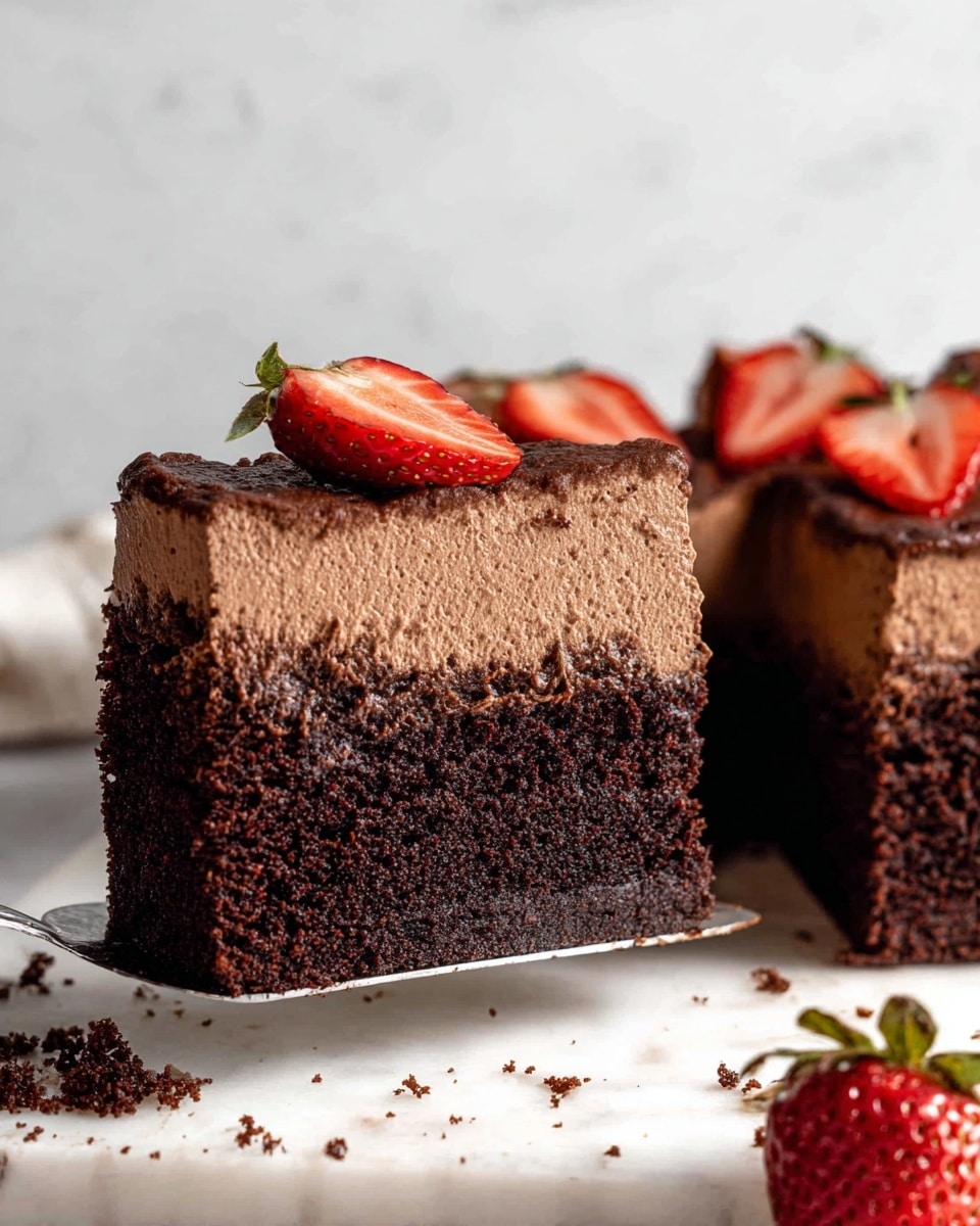 A close-up view of a two-layer chocolate cake slice being lifted by a spatula, showing a thick bottom layer of dark brown, moist chocolate cake with a dense texture, topped by a thick upper layer of light brown, smooth chocolate mousse with a slightly soft and creamy texture, sitting next to the remaining cake on a white marbled surface. Fresh red strawberries, one sliced in half and one whole on the cake, add a pop of bright color. Crumbs are scattered on the surface under the slice. The photo taken with an iphone --ar 4:5 --v 7