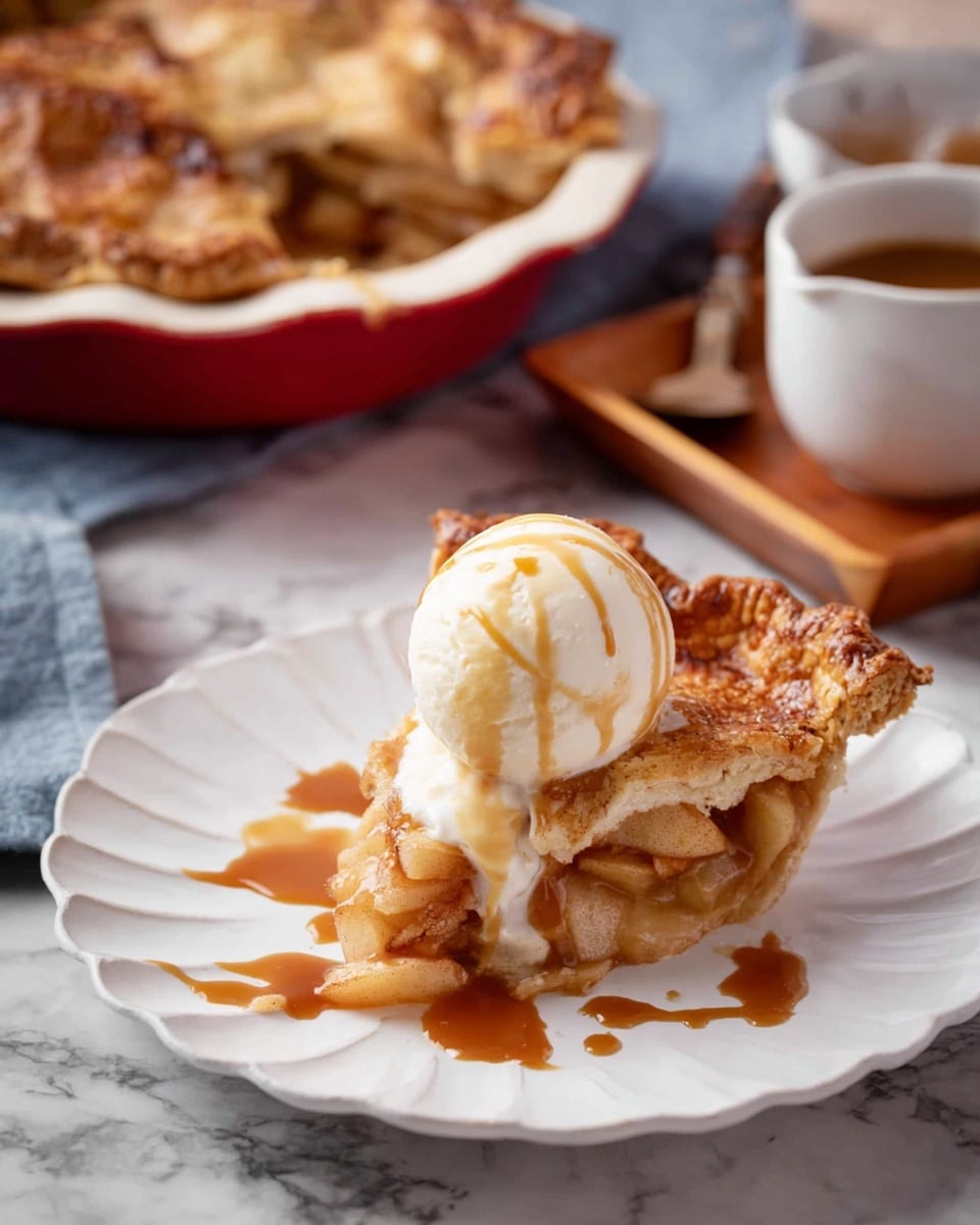 A slice of golden brown apple pie with a crispy crust sits on a white scalloped plate, topped with a round scoop of white vanilla ice cream that is slowly melting and dripping down the pie, with light brown caramel sauce drizzled over the ice cream and pie. The pie filling is warm with visible soft apple pieces inside a thick, flaky crust. In the background, there is a red pie dish with more pie and a small white cup with caramel sauce on a wooden tray, all set on a white marbled surface. Photo taken with an iphone --ar 4:5 --v 7