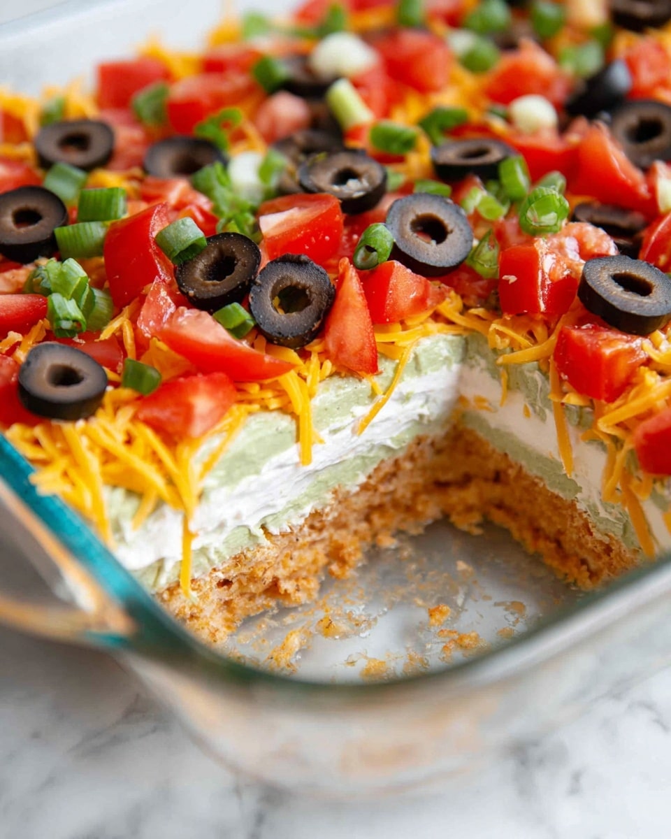 A clear glass rectangular dish shows a colorful layered dip. The bottom layer is green and smooth, likely avocado or guacamole. Above it, a layer of dark red beans or salsa is spread evenly. Then, a thick layer of bright orange shredded cheese covers the dish. On top, there are scattered black olive rings, chopped red tomatoes, and small pieces of green onions. The dish is set on a white marbled surface. photo taken with an iphone --ar 4:5 --v 7