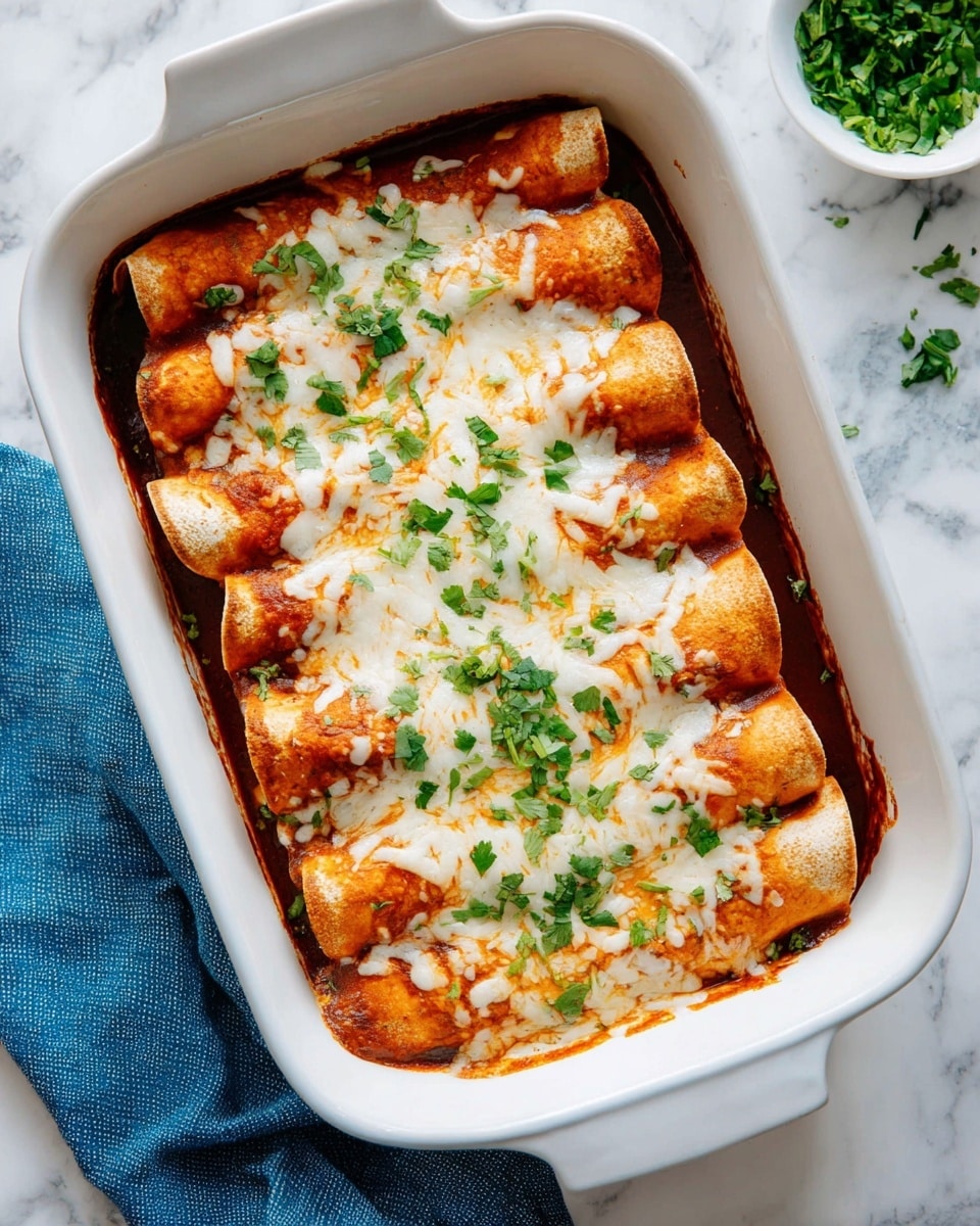 A white rectangular baking dish holds five rolled tortillas tightly placed side by side. The tortillas are light brown and soft in texture. They are covered with a layer of rich red sauce that peeks out around the edges and between the tortillas. On top, there is a thick layer of melted white cheese, slightly browned in some spots, providing a creamy texture. Scattered across the cheese are small pieces of fresh green cilantro, adding a pop of color. The dish is set on a white marbled surface with a blue cloth napkin beside it and a small white bowl of chopped green herbs in the background. Photo taken with an iphone --ar 4:5 --v 7