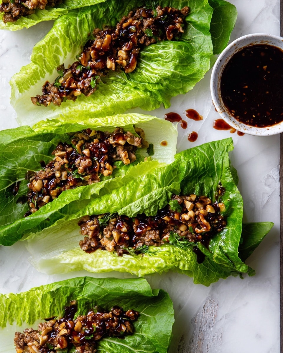 There are several fresh lettuce wraps laid out on a white marbled surface, each made with two layers of large, crisp, green lettuce leaves; the outer leaves are darker green while the inner leaves are lighter green with visible veins. Inside each wrap is a finely chopped mixture that looks like mushrooms and nuts, all in different shades of brown. A shiny dark sauce is drizzled over the filling, creating a slight gloss. On the top right corner, there is a small white bowl filled with more dark sauce, some spilled on the edge. The scene looks natural and fresh with no utensils or other items visible. photo taken with an iphone --ar 4:5 --v 7