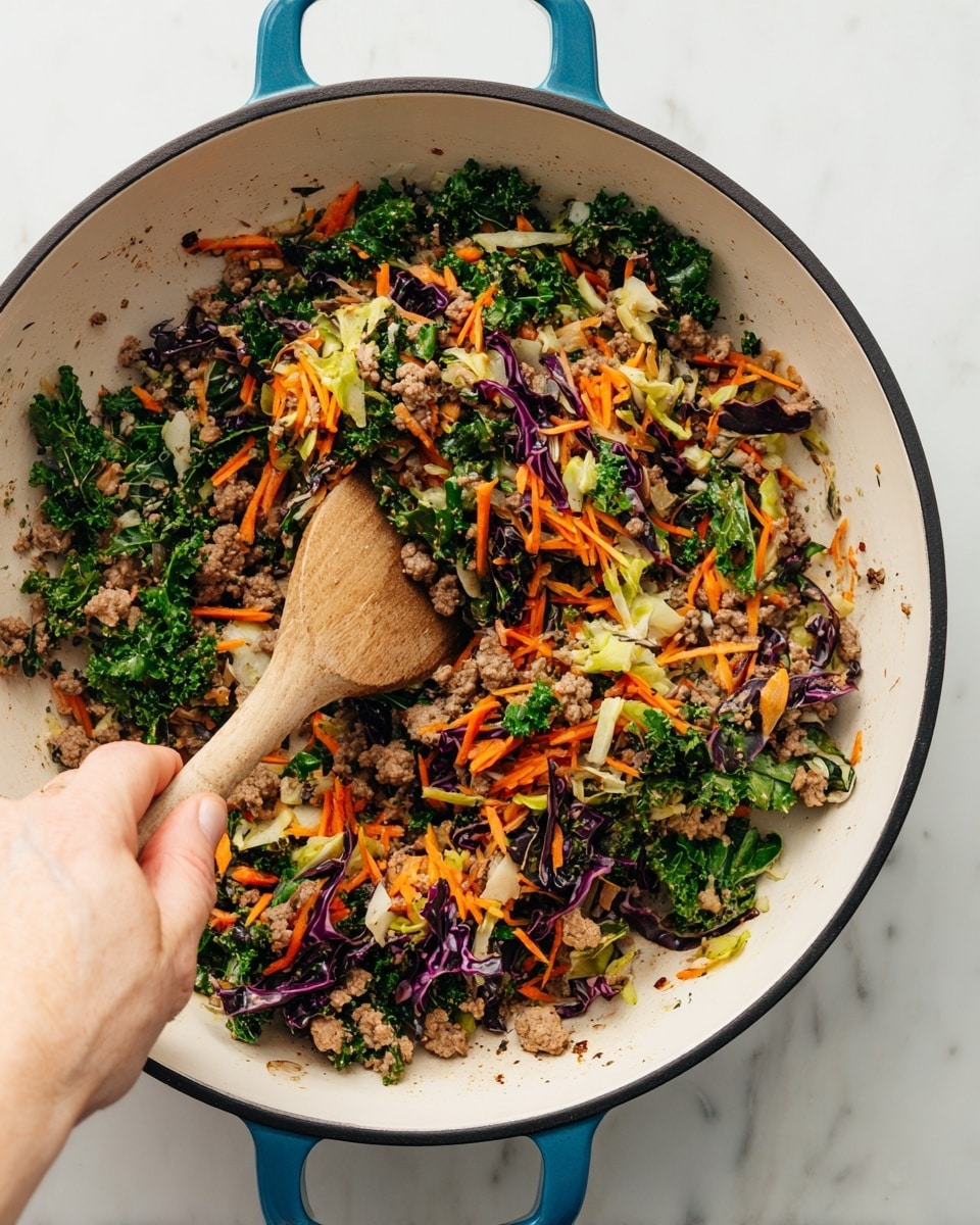 The image shows a close-up of a large white enamel pan with a black rim and bright blue handles sitting on a white marbled surface. Inside the pan, there is a colorful mix of cooked ground meat, shredded orange carrots, chopped green kale, bits of purple cabbage, and some light yellow vegetables. A wooden spoon is partly inside the pan, stirring the mixture. A woman's hand is holding the wooden spoon near the bottom left corner of the image, showing a gentle grip. The vegetables and meat are distributed evenly across the pan, creating a vibrant, textured look. photo taken with an iphone --ar 4:5 --v 7