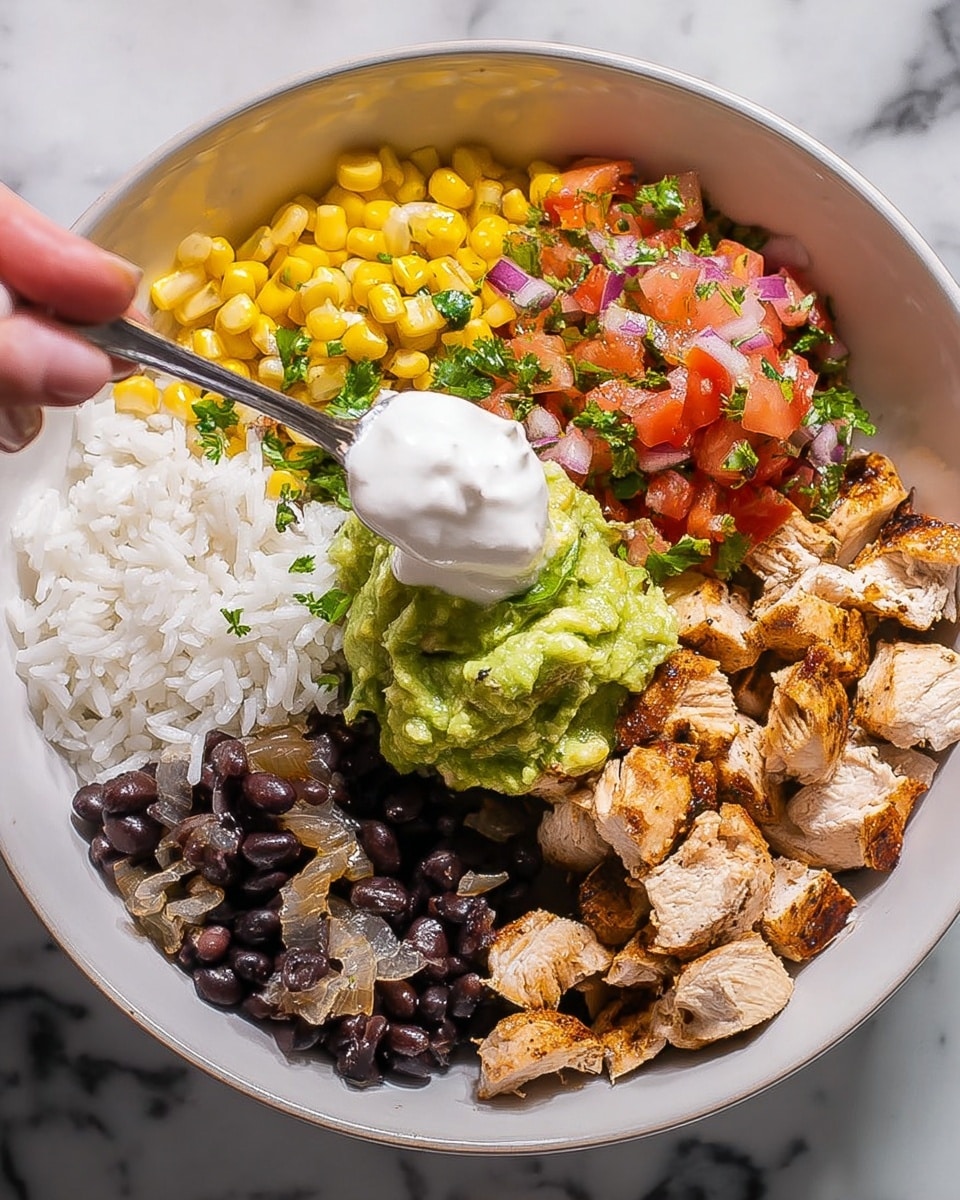 A white bowl with four main layers of food on a white marbled surface: at the bottom is white rice, topped with five sections arranged in a circle. In the top right are chunks of grilled light brown chicken. Below them are dark black beans mixed with small pieces of cooked onions. To the left of the beans is a bright green scoop of chunky guacamole. Above the guacamole is a vibrant red mix of diced tomatoes with some herbs. At the top left is a mix of yellow corn, green cilantro leaves, and small bits of red onion. A spoon held by a woman's hand is adding a dollop of white sour cream on the chicken. photo taken with an iphone --ar 4:5 --v 7